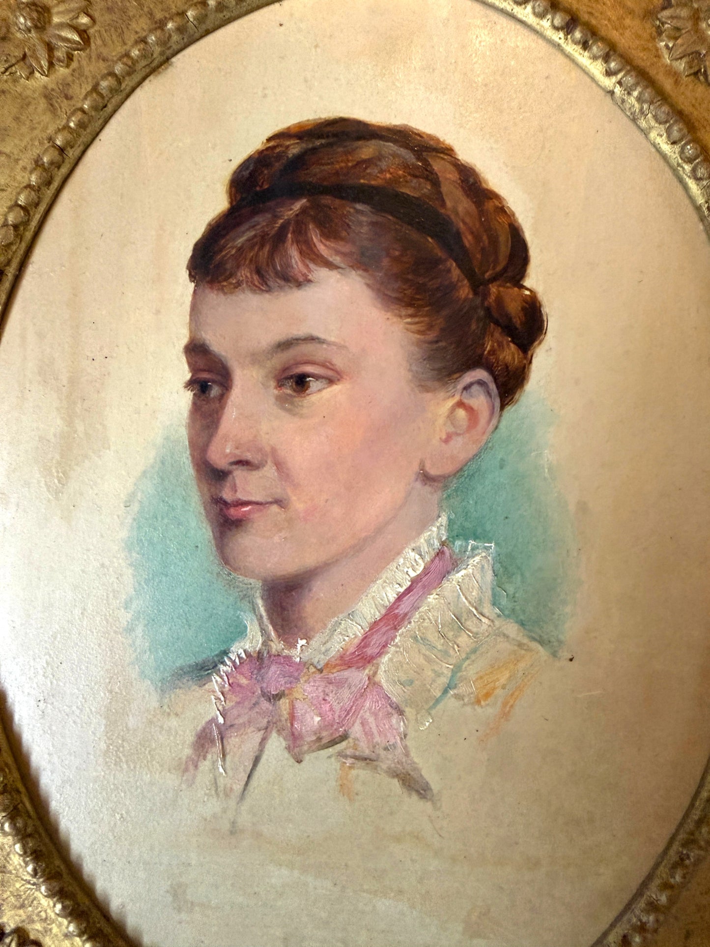 Hinson Vintage Interiors antique oval portrait of a woman in an ornate gold frame with floral and scrollwork details.