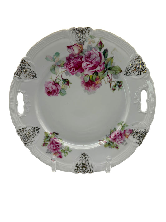 Hinson Vintage Interiors porcelain cake plate with pink roses, green leaves, and black-and-gold scroll accents.