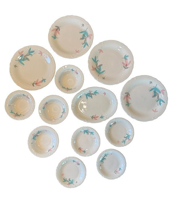 Hinson Vintage Interiors 13-piece Shenango China set with white ceramic plates and bowls featuring pink and teal leaves.