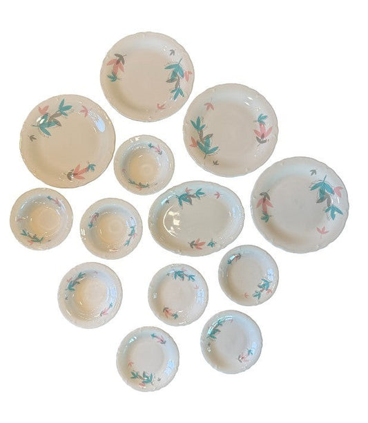 Hinson Vintage Interiors 13-piece Shenango China set with white ceramic plates and bowls featuring pink and teal leaves.