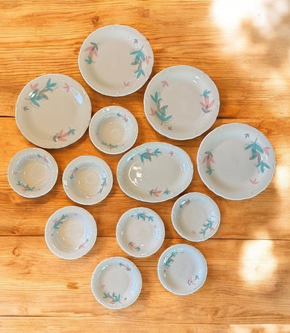 Hinson Vintage Interiors 13-piece Shenango China set featuring white ceramic plates and bowls with pink and teal leaf motifs.